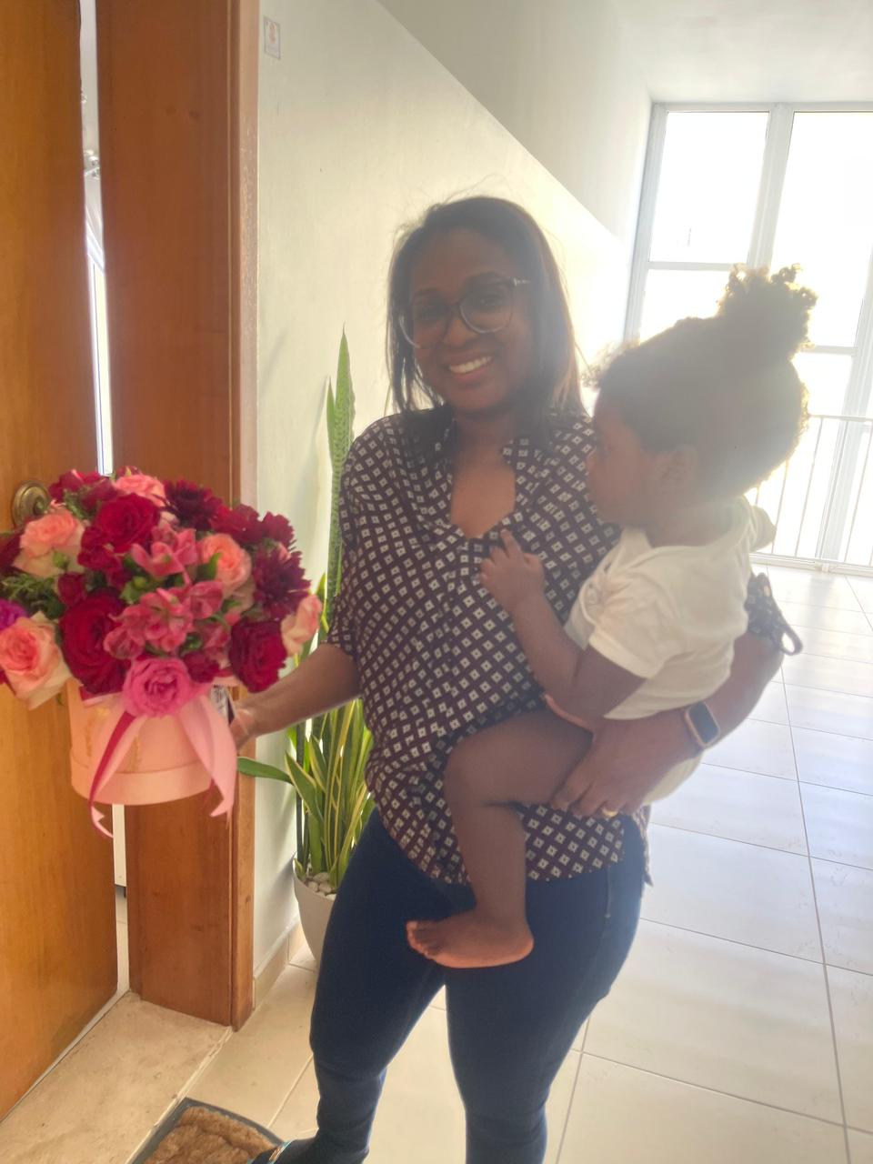 Mãe com bebé e arranjo rosa